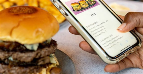 Picture of a mobile phone screen and a burger near it 