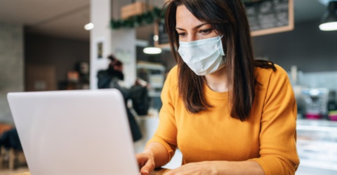 Woman using computer wearing a mask